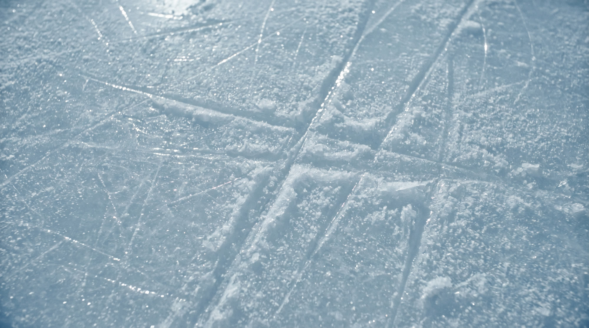 Macro detail of freshly cut arena ice, crossed with skate blade tracks