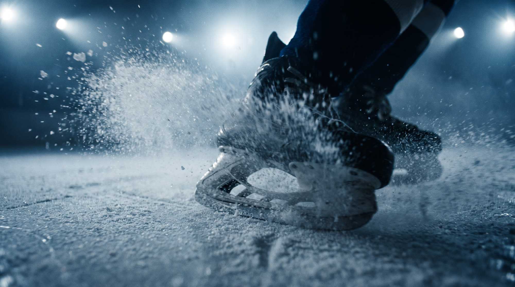 Skate carving into the ice, throwing a spray of shards