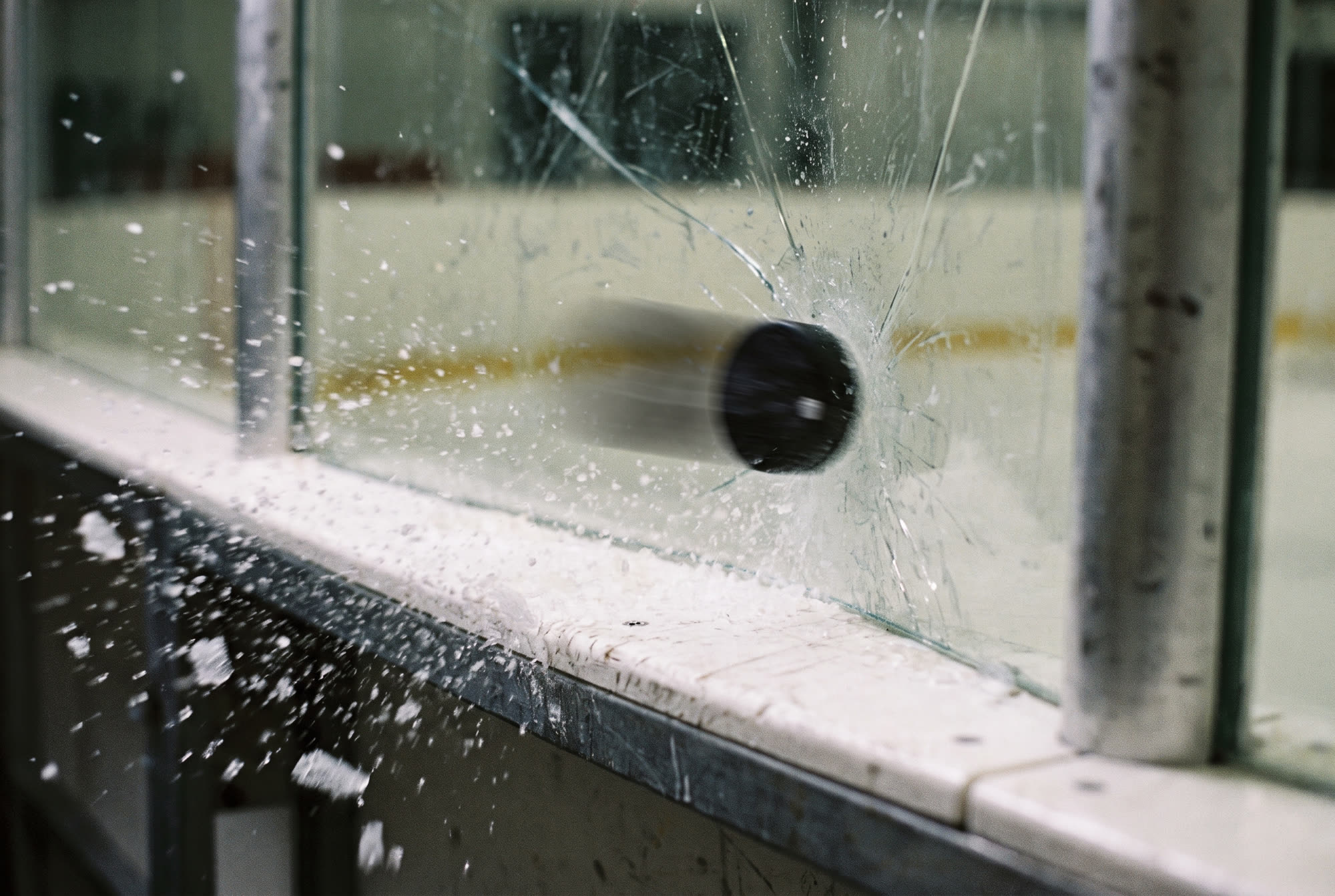 A puck exploding off the boards behind the glass
